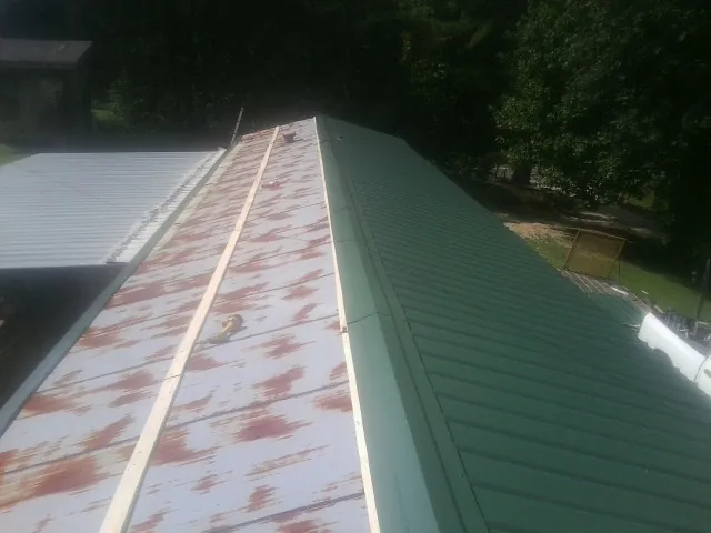 Old rusted panels beside newly installed green metal roofing — Wind Damage Roof Repair by Roofing Brothers in Oley