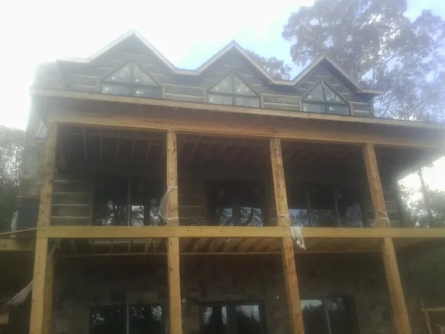 Dormers and porch framing on a large log home under construction — Roof Coating work by our crew in Oley